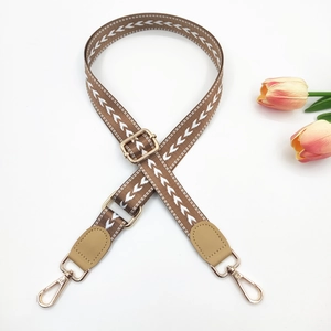Detail of adjustable arrow pattern strap with golden metal hooks and leather accents