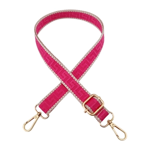 Close-up of pink geometric woven bag strap with polished gold lobster clasps and buckles