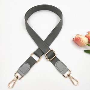 Detail of adjustable grey cotton bag strap with gold metal lobster clasps and leather trim