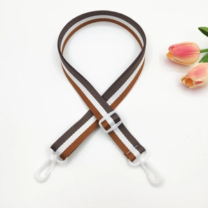 Detail view of striped nylon bag strap with white plastic buckles and adjustable slide