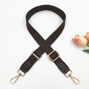 Detail of adjustable coffee brown fabric shoulder strap with gold metal buckle and leather end