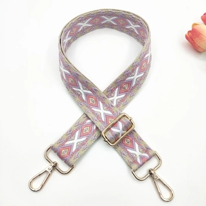 Detail of embroidered geometric diamond bag strap with golden metal swivel hooks