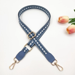 Macro view of adjustable woven strap with white arrow pattern and gold-tone metal hardware