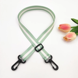 Detail of adjustable 2.5cm green and white striped bag strap with black plastic swivel hooks