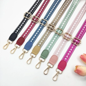Close-up of adjustable woven arrow pattern bag straps with gold metal hooks and hardware