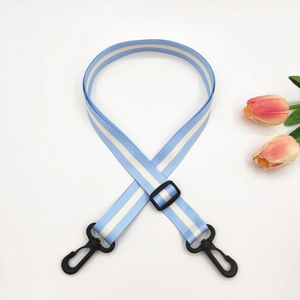 Detail of adjustable blue and white striped bag strap with durable black plastic hooks