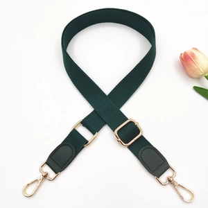 Detail of dark green adjustable cotton strap with gold metal hooks and leather joints