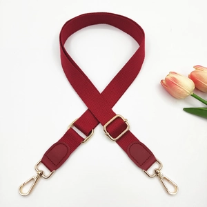 Macro view of red canvas bag strap with gold lobster clasps and adjustable buckle
