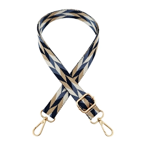 Detail of adjustable woven bag strap with blue and brown geometric patterns and gold clips