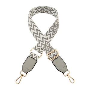 Detail view of adjustable bag strap with grey geometric pattern and gold-tone metal hooks
