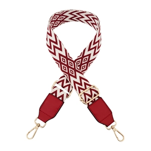 Close-up of geometric wave pattern woven bag strap with red leather ends and gold buckle
