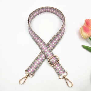 Close-up of pink and grey woven geometric bag strap with adjustable gold metal hardware