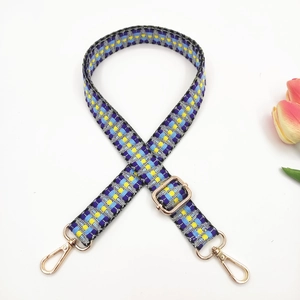 Macro view of colorful geometric woven bag strap with golden metal rotating hooks