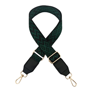Detail of adjustable 3.8cm wide bag strap with dark green geometric pattern and gold hardware