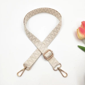 Detail of adjustable beige woven strap with polished gold-tone metal lobster clasps