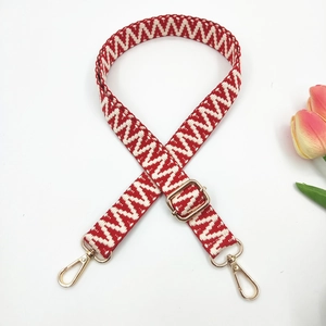 Detail of adjustable 2.5cm woven strap with red geometric patterns and gold lobster clasps