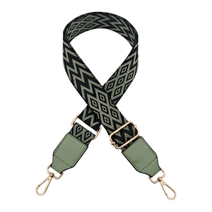 Detail of adjustable bag strap showing green diamond pattern and gold metal hooks
