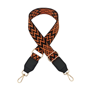 Detail of adjustable woven shoulder strap with orange geometric pattern and gold hooks