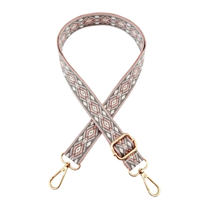 Detail of pink geometric woven shoulder strap with gold metal lobster clasps and buckles