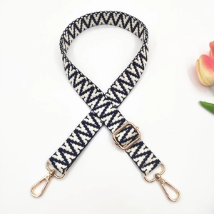 Close-up of black and white bohemian woven bag strap with golden metal lobster clasps