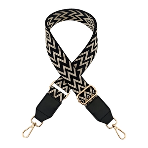 Close-up of adjustable wide shoulder strap with black and white wavy pattern and gold hooks