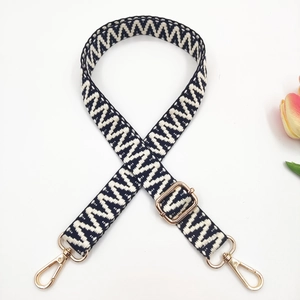 Close-up of woven bag strap featuring black and white chevron pattern and gold metal hardware