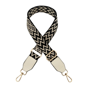 Detail of adjustable wave pattern bag strap with cream leather and gold metal buckles