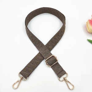 Macro detail of 2.5cm woven bag strap with geometric patterns and gold swivel hooks