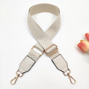 Detail view of cream white woven guitar strap with herringbone pattern and gold hooks