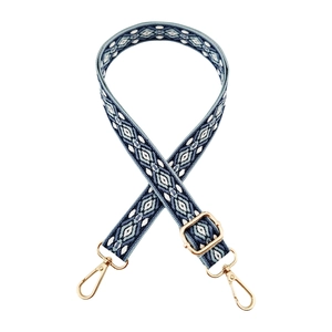 Macro detail of geometric jacquard shoulder strap with gold metal lobster clasps
