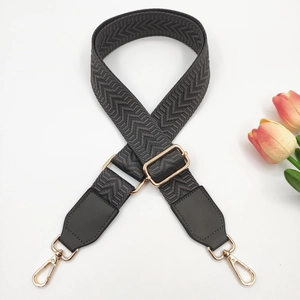 Detail of dark grey herringbone woven strap with golden metal buckles and leather ends