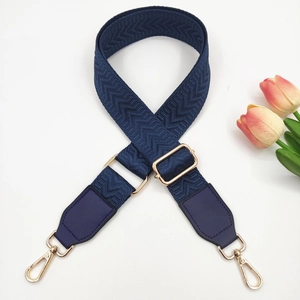 Detail of adjustable dark blue 3.8cm wide bag strap with gold metal buckles and pattern