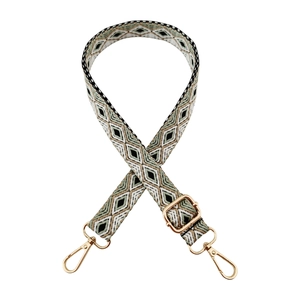 Detail of adjustable woven bag strap with green geometric pattern and gold buckles