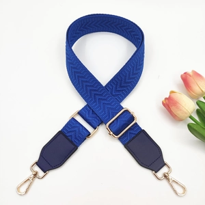 Detail of royal blue woven bag strap with golden metal swivel hooks and adjustment buckle