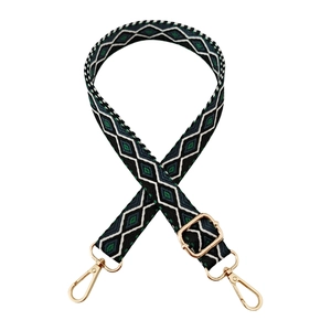 Macro detail of 2.5cm jacquard bag strap featuring green geometric diamond pattern and gold metal hooks