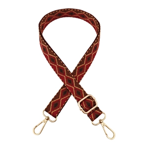 Detail of red jacquard cross-body strap with geometric pattern and gold hardware
