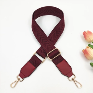Macro detail of wine red chevron strap with gold buckles and faux leather ends
