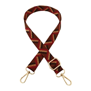Detail of adjustable woven bag strap with geometric patterns and gold metal hardware