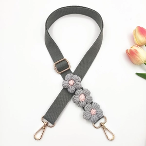 Detail of grey canvas strap featuring handmade crochet flowers and gold metal hardware