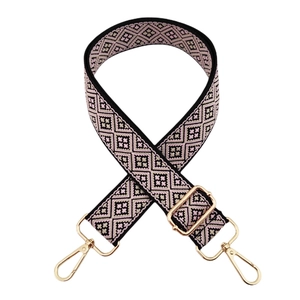 Detail of adjustable woven bag strap with pink and black geometric pattern and gold hooks