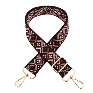 Close-up of geometric woven strap with gold metal lobster clasps and adjustable buckle