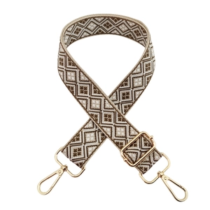 Close-up of geometric jacquard woven strap with golden metal swivel hooks and buckles