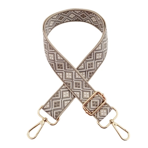 Close-up of adjustable woven strap with beige geometric pattern and gold-tone metal hooks