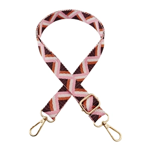 Detail of adjustable geometric jacquard bag strap with golden metal hardware buckles