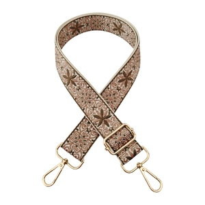 Macro view of adjustable woven ethnic strap with floral embroidery and gold metal hooks
