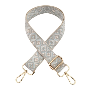 Detail of adjustable geometric jacquard bag strap with golden metal hardware clips