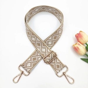 Close-up of adjustable woven shoulder strap with geometric patterns and gold metal buckles