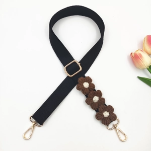 Detail of adjustable black bag strap with crochet flowers and golden metal buckles