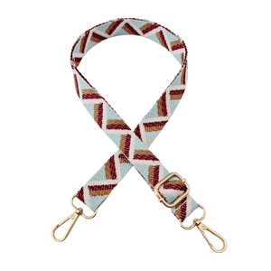 Close-up of woven bag strap with geometric patterns and golden metal swivel hooks