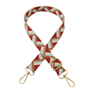 Detail of adjustable colorful jacquard strap with red zigzag pattern and gold metal hooks